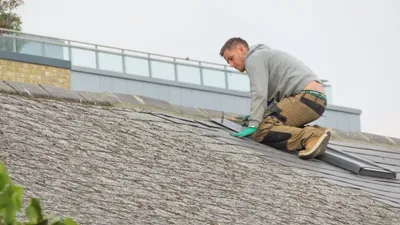 Professional roofer carefully working on roof tiles